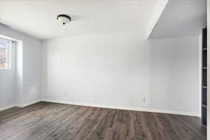 Empty room featuring dark wood-style floors and baseboards