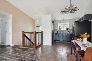 Kitchen featuring freestanding refrigerator, light countertops, hanging lights, backsplash, and dark wood-type flooring