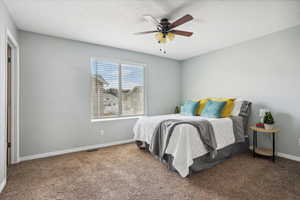 Bedroom with a ceiling fan and dark colored carpet