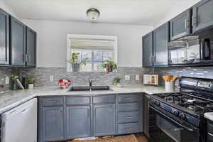 Kitchen featuring black appliances, gray cabinetry, tasteful backsplash, and a textured ceiling