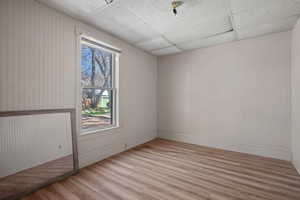 Empty room with light wood-style flooring and a drop ceiling