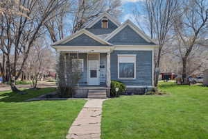View of front of house with a front lawn, a porch, and a shingled roof