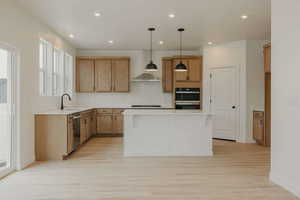Kitchen featuring decorative light fixtures, a kitchen island, light wood-style flooring, and wood finish cabinetry