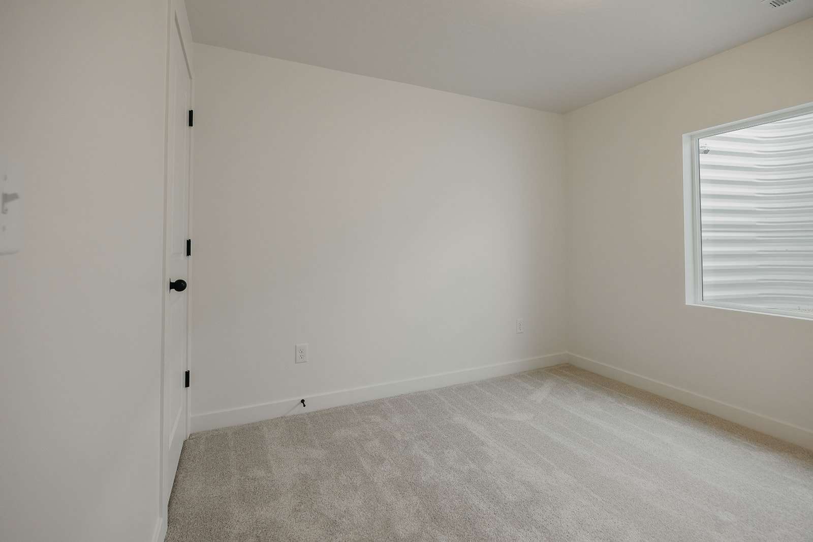 Unfurnished room featuring light carpet and baseboards