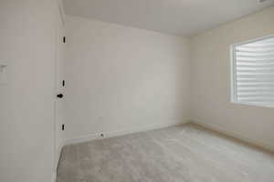 Unfurnished room featuring light carpet and baseboards
