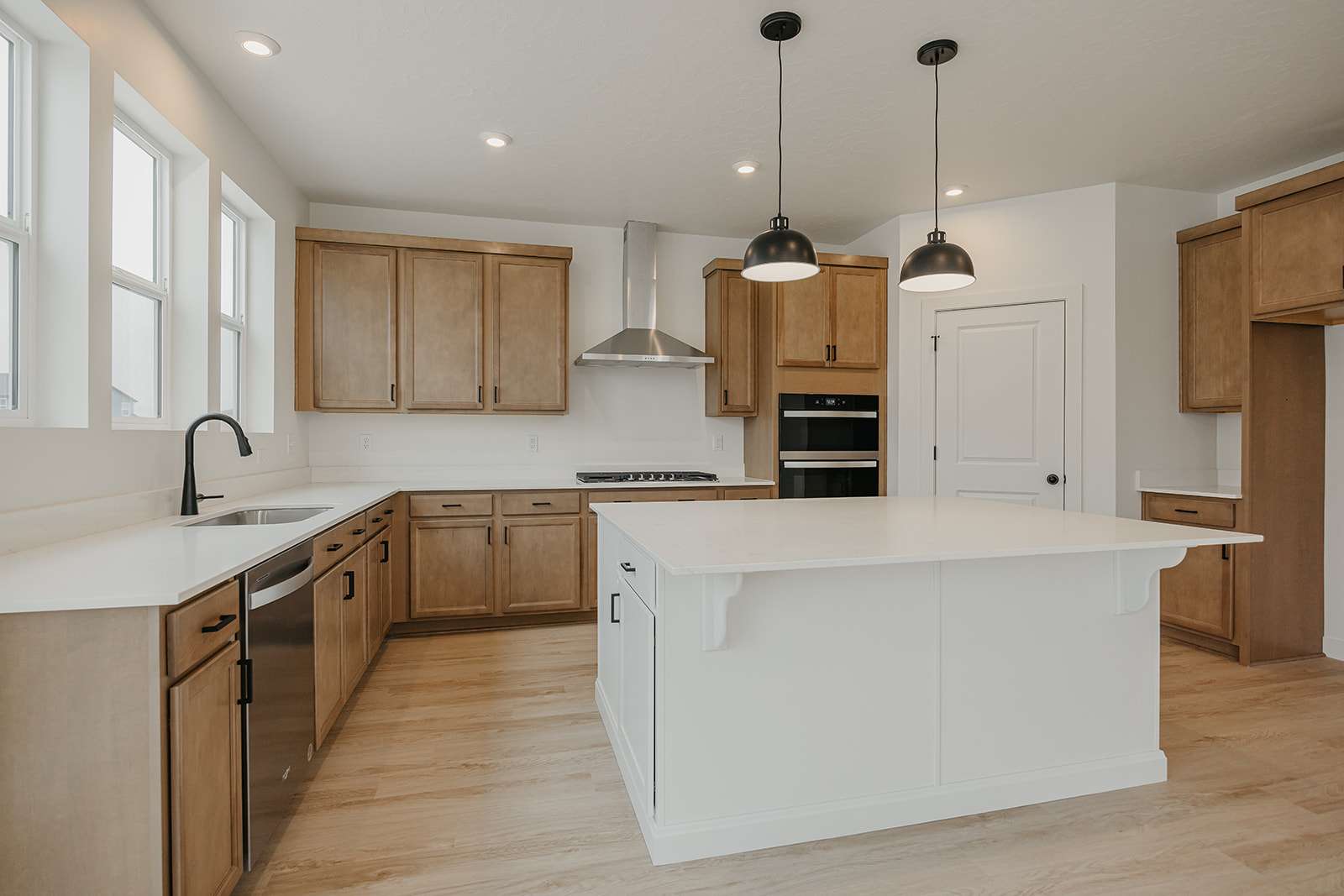 Dual tone kitchen featuring a kitchen island, hanging light fixtures, dishwasher, light wood finished floors, and two tone cabinetry
