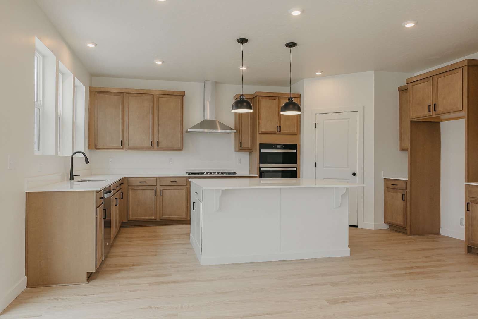 Kitchen featuring a kitchen island, light wood-style flooring, pendant lighting, two tone cabinets, and a breakfast bar
