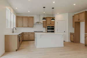 Kitchen featuring a kitchen island, light wood-style flooring, pendant lighting, two tone cabinets, and a breakfast bar