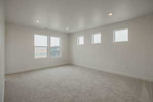 Empty room with light carpet and recessed lighting