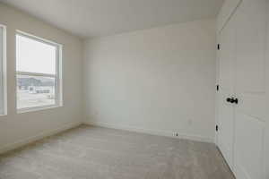Unfurnished bedroom with light colored carpet and a closet
