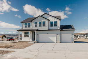 View of front of house featuring covered porch, a shingled roof, board and batten siding, and driveway
