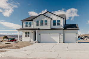 View of front facade featuring a porch, concrete driveway, board and batten siding, a garage, and a shingled roof