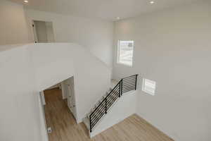 Stairway with wood finished floors, recessed lighting, and a high ceiling