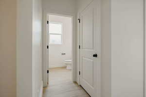 Corridor with light wood-type flooring and baseboards