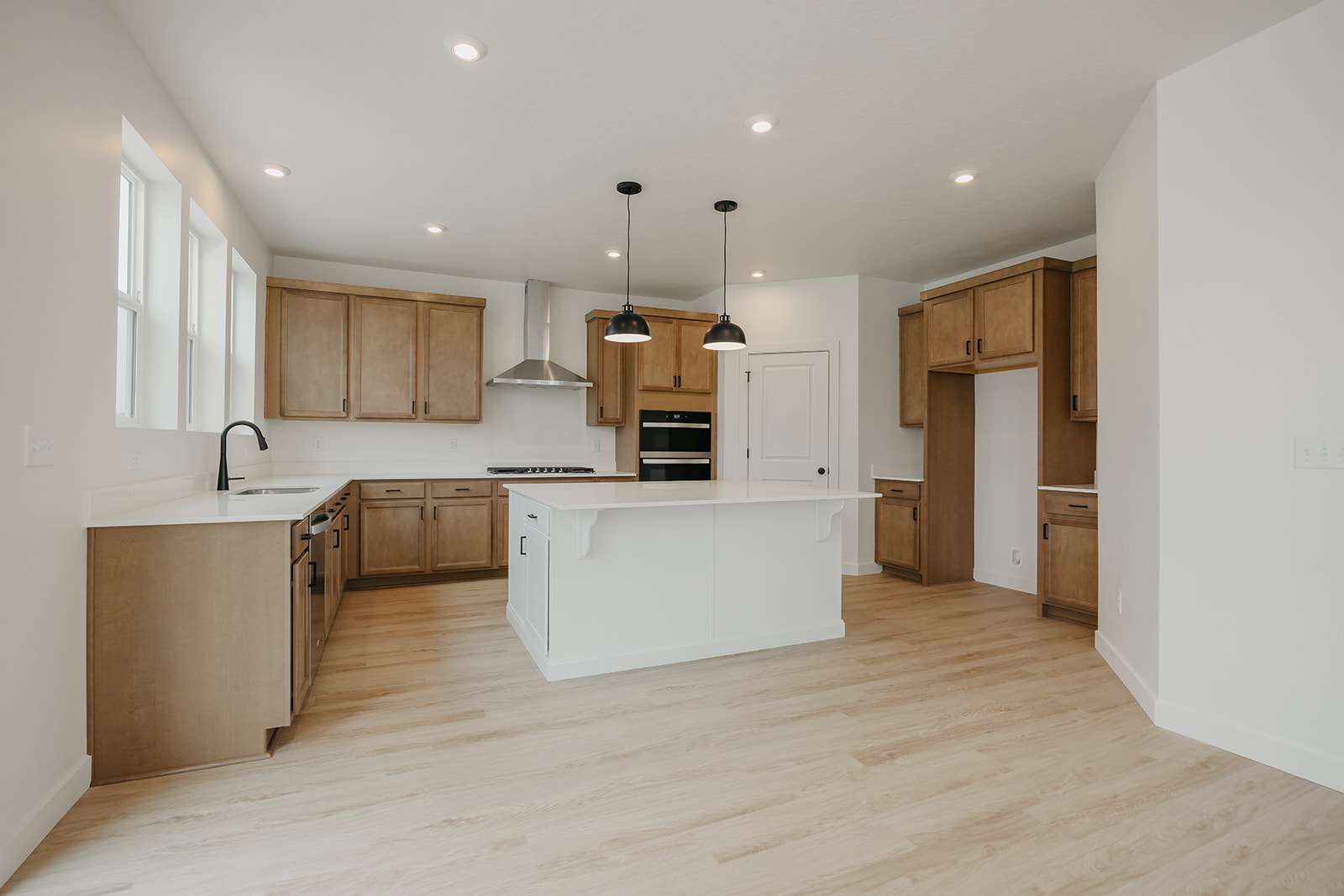 Kitchen with light wood finished floors, a kitchen island, decorative light fixtures, a kitchen breakfast bar, and two tone cabinets