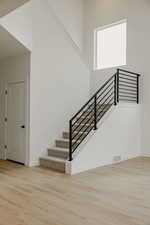 Stairs with wood finished floors and a high ceiling