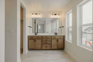 Full bath featuring double vanity and baseboards