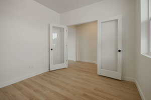 Spare room with light wood finished floors and french doors