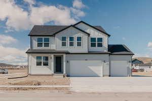 View of front of property featuring roof with shingles, board and batten siding, and concrete driveway