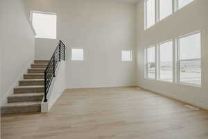 Stairs with healthy amount of natural light, wood finished floors, and a high ceiling