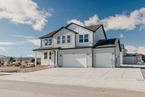 View of front facade with board and batten siding, driveway, a porch, an attached garage, and roof with shingles