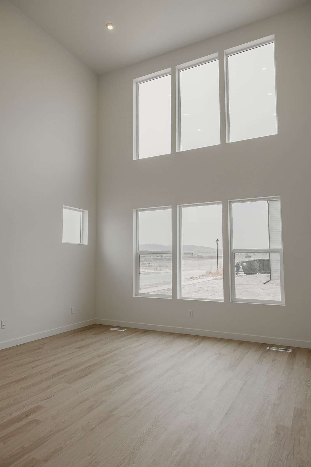 Unfurnished room featuring a high ceiling, plenty of natural light, light wood-type flooring, and recessed lighting