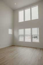 Unfurnished room featuring a high ceiling, plenty of natural light, light wood-type flooring, and recessed lighting