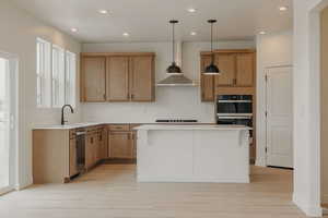 Kitchen featuring pendant lighting, wood finish cabinets, a kitchen island, multiple ovens, and a kitchen bar