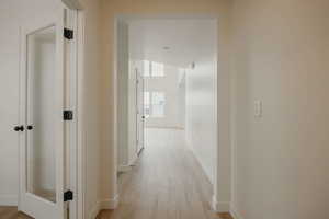 Corridor with light wood-type flooring and baseboards