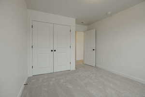 Unfurnished bedroom with light carpet and a closet