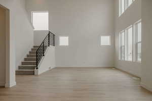 Unfurnished living room with a high ceiling and light wood-type flooring