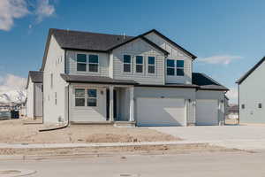 View of front facade featuring a shingled roof, driveway, a garage, and board and batten siding