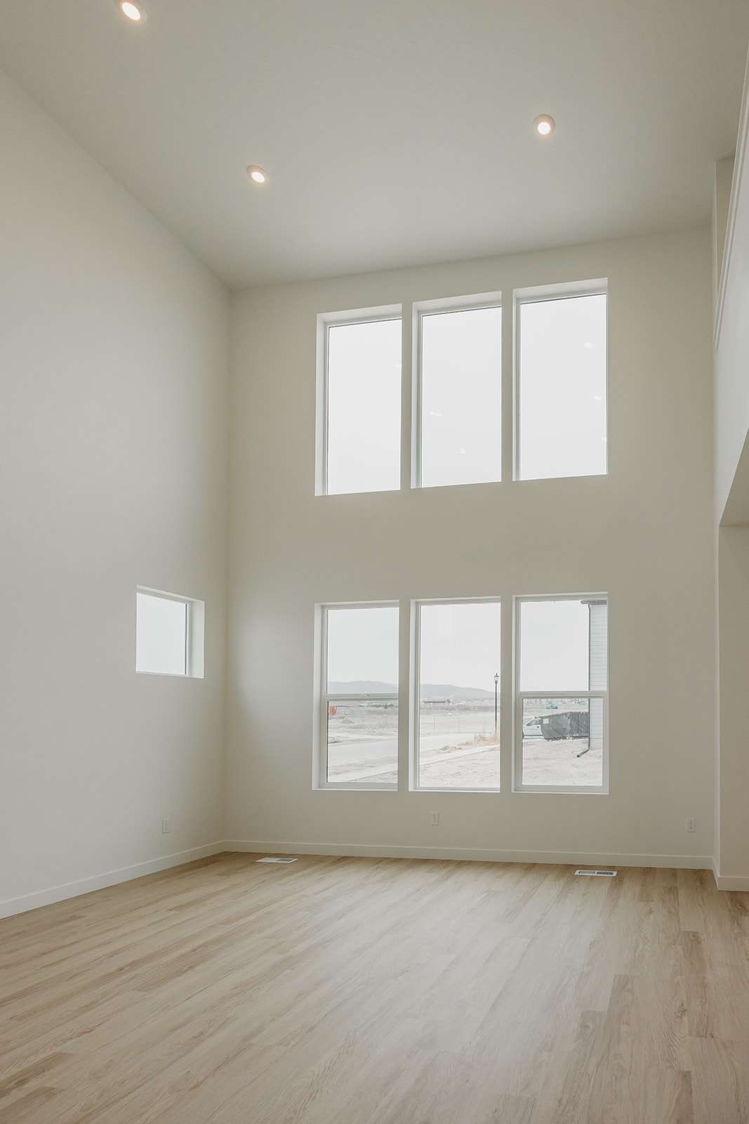 Unfurnished room featuring a high ceiling, light wood finished floors, recessed lighting, and healthy amount of natural light
