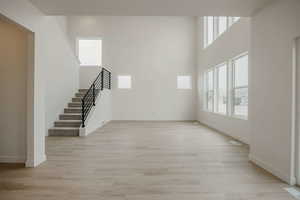 Unfurnished living room with light wood-style flooring and a high ceiling