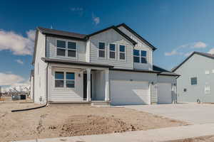 View of front of home featuring covered porch, driveway, an attached garage, and board and batten siding
