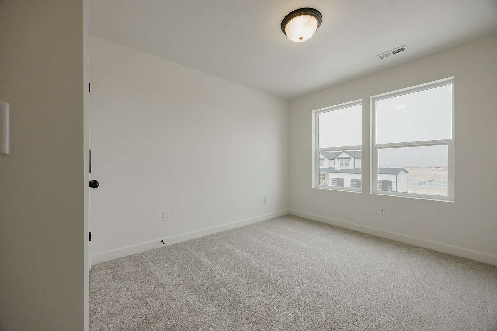 Empty room with light colored carpet and baseboards