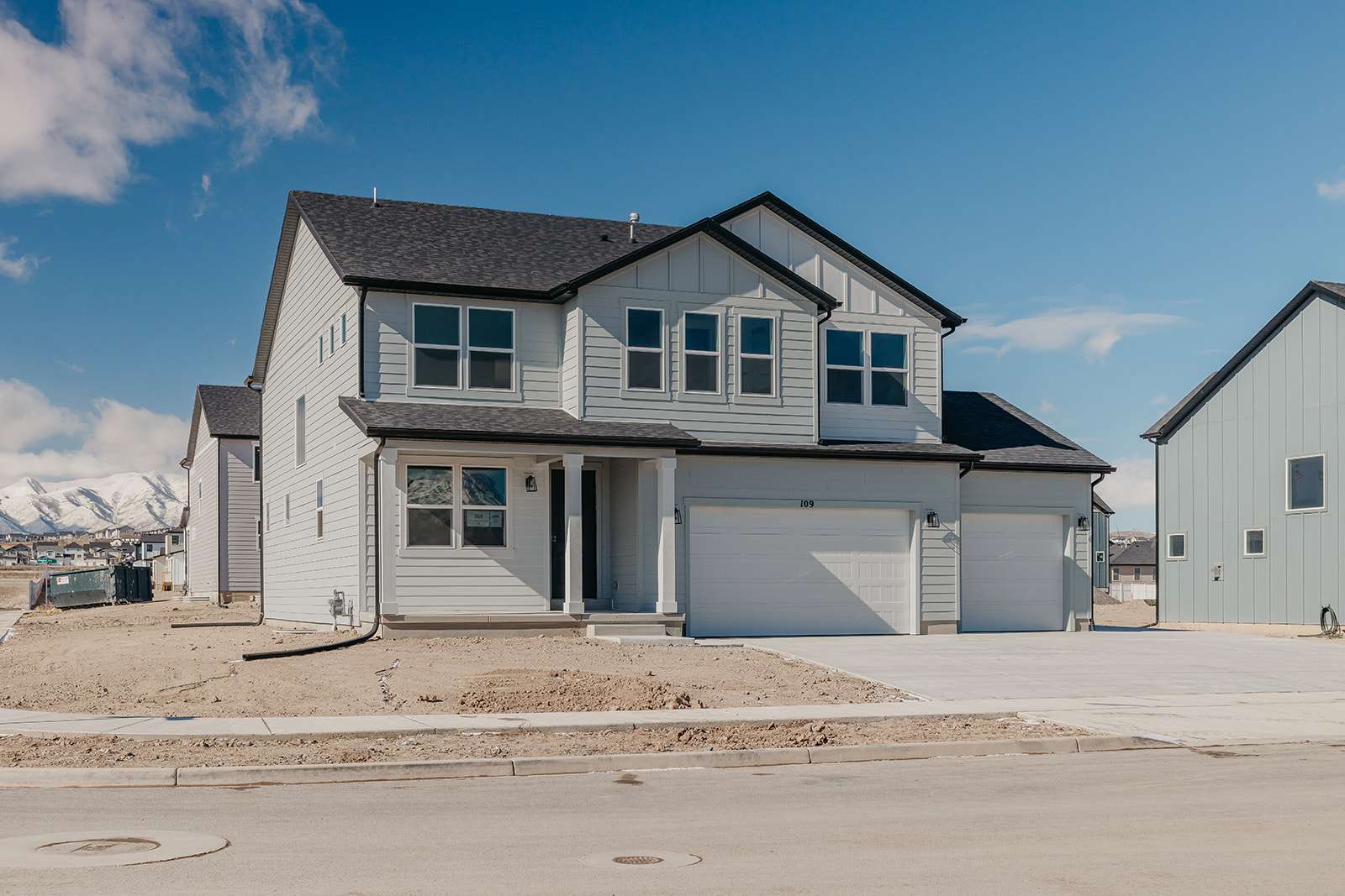 View of front of property with a shingled roof, driveway, a garage, covered porch, and board and batten siding