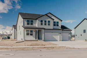 View of front of property with a shingled roof, driveway, a garage, covered porch, and board and batten siding