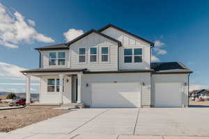 View of front of house with covered porch, driveway, board and batten siding, and an attached garage