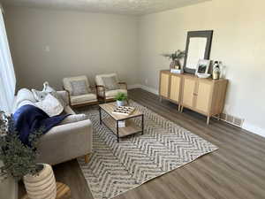 Living area featuring dark wood-style flooring and a textured ceiling