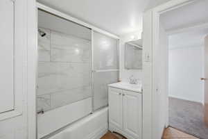 Full bathroom featuring vanity, enclosed tub / shower combo, and light carpet