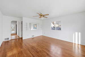 Spare room featuring ceiling fan, arched walkways, and wood finished floors