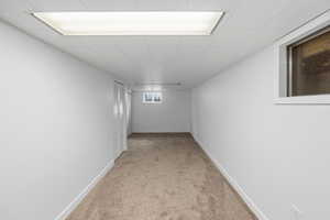 Corridor with baseboards and light colored carpet