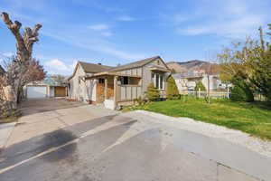 View of front of home with an outbuilding, a detached garage, a mountain view, and a shingled roof