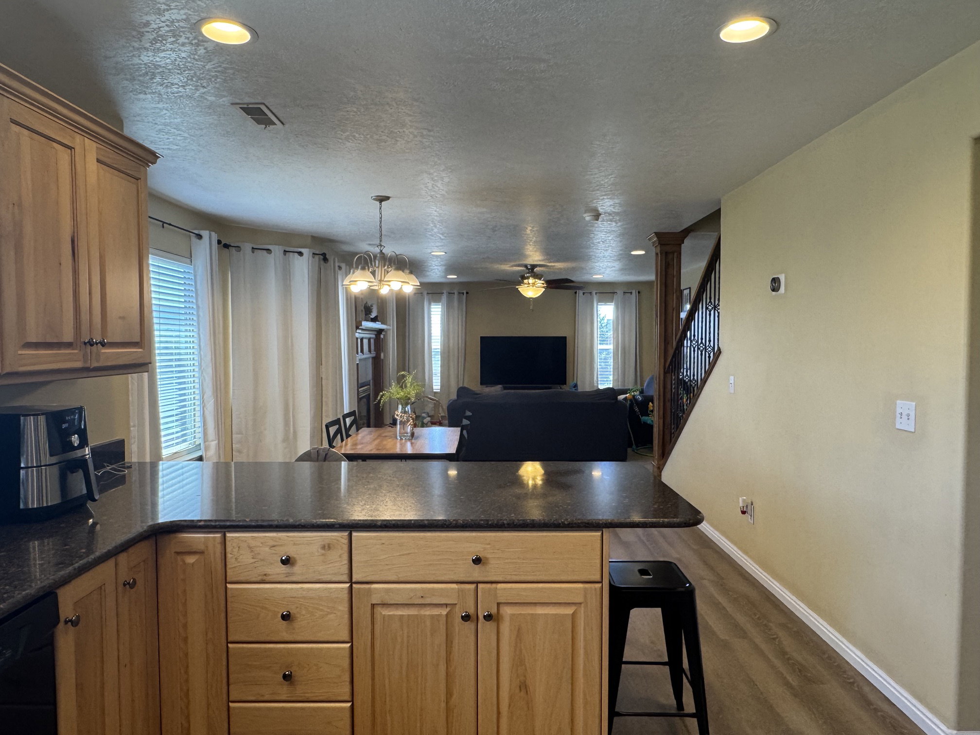 Kitchen island with a dark countertop and light wood-finish cabinetry, featuring integrated recessed lighting