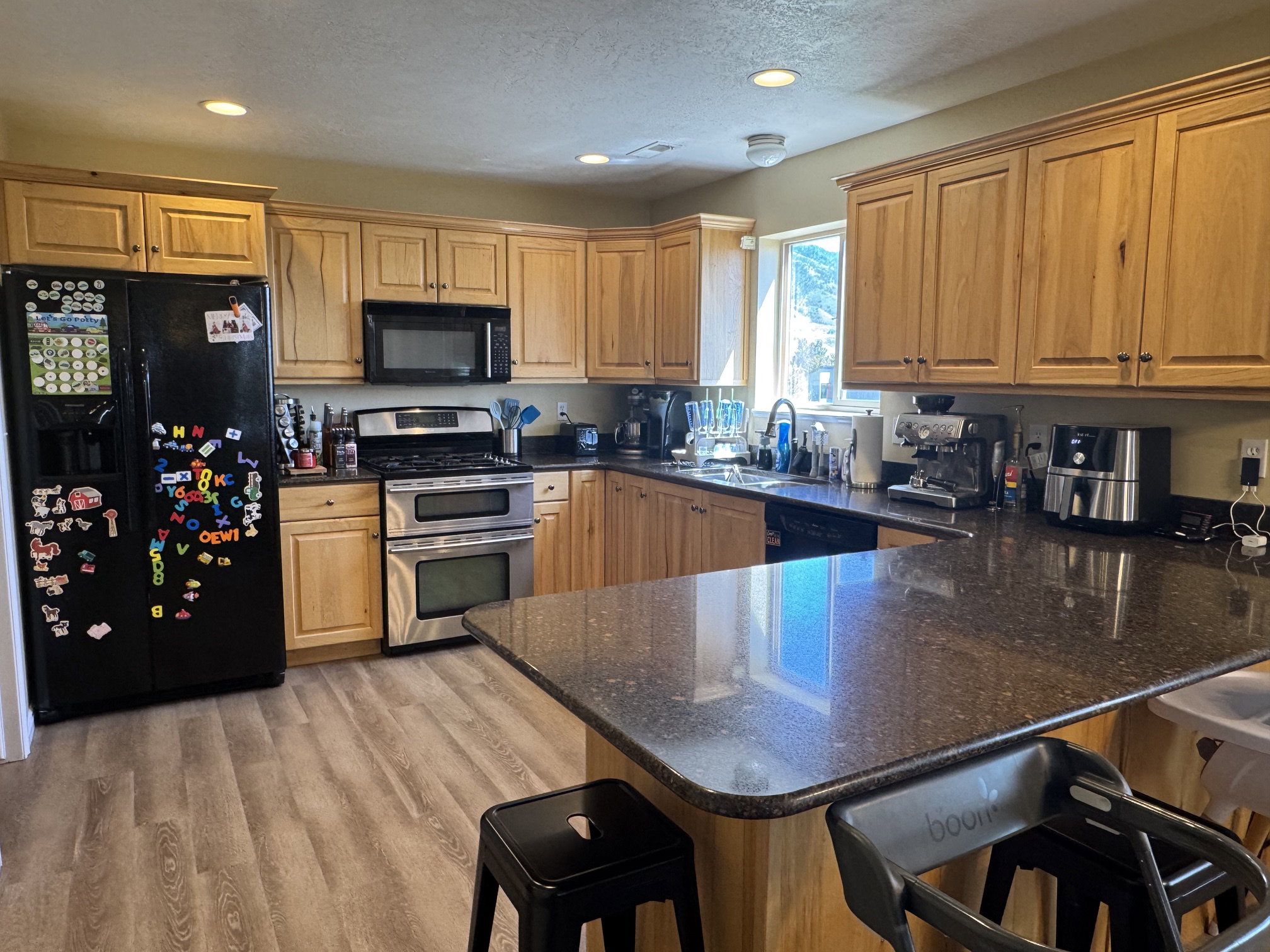 Kitchen featuring natural wood cabinetry, dark speckled countertops, and wood-finish flooring