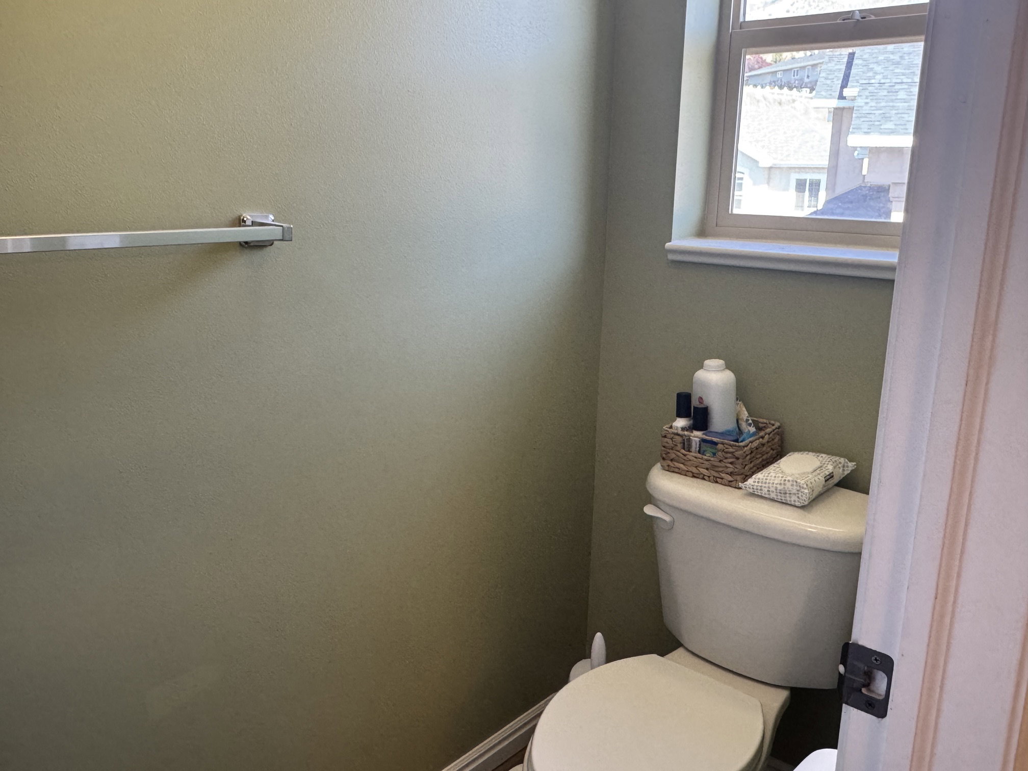 Bathroom featuring a white toilet, single window, and a wall-mounted towel bar
