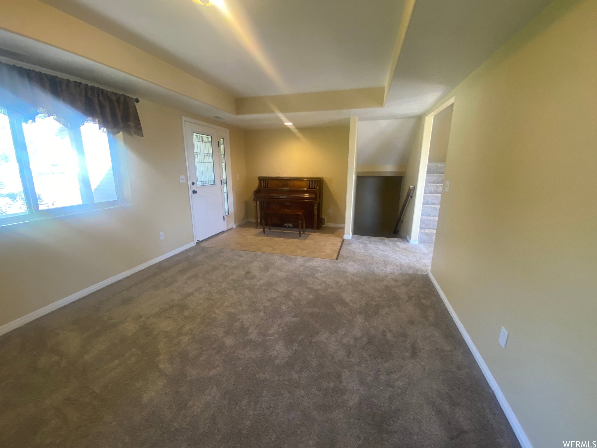 Unfurnished living room with carpet floors and a raised ceiling
