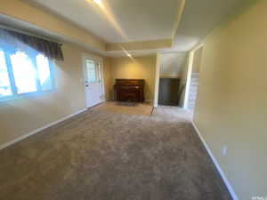 Unfurnished living room with carpet floors and a raised ceiling