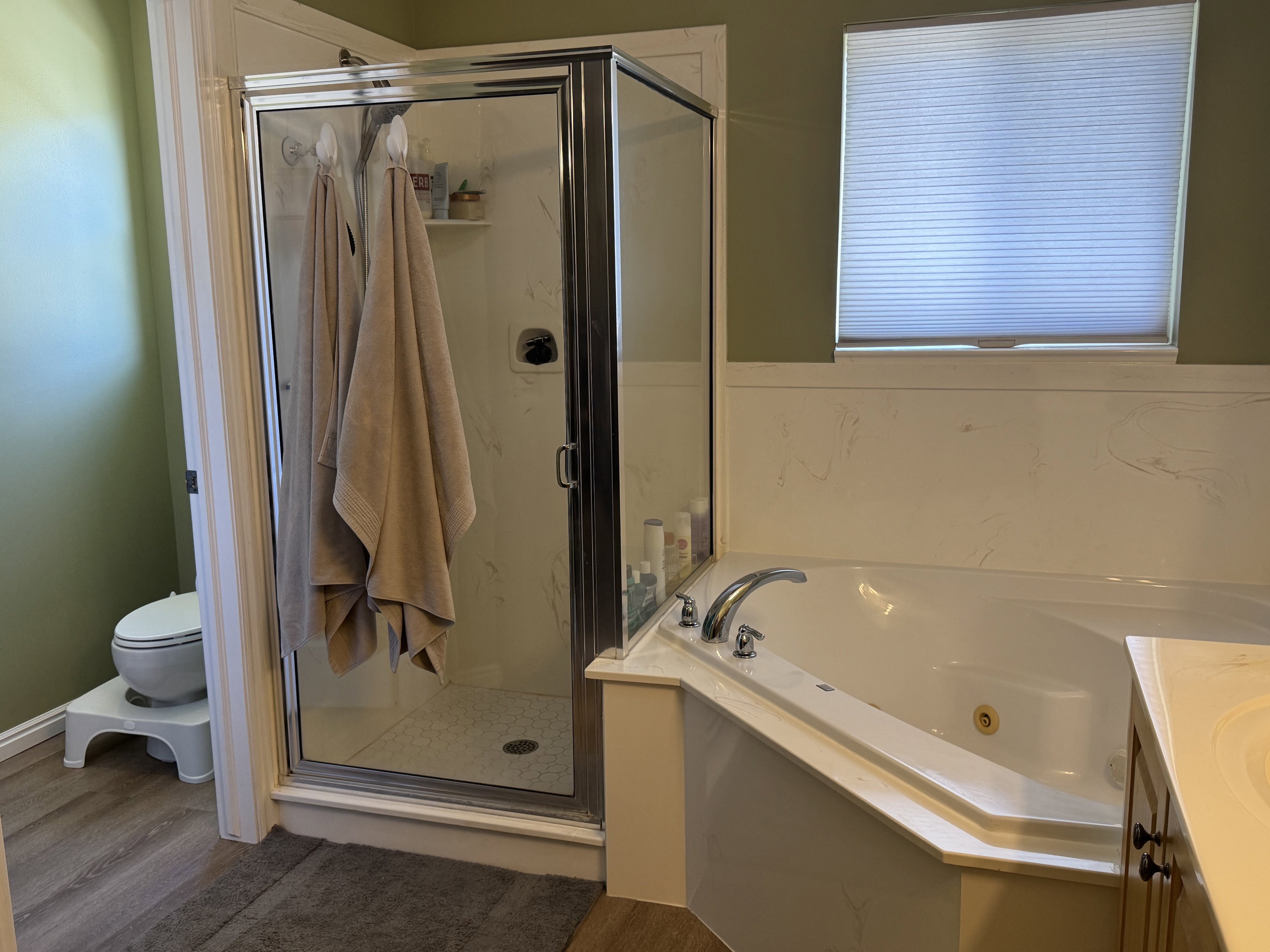 Corner soaking tub with stainless steel fixtures and a privacy window blind
